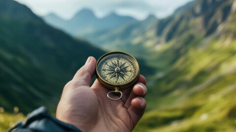 Een ouderwets kompas met draaischijf in hand en op de achtergrond een berglandschap